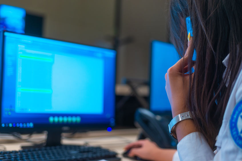 Security data center operator looking at the monitor while talking on a phone.